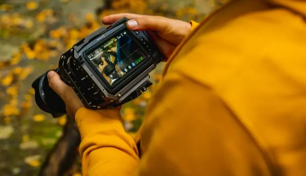 Person holding a camera to record video footage outdoors using Visla for Marketers, showcasing Visla's capabilities in helping marketers capture high-quality footage for their campaigns.